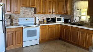 Una cocina con armarios de madera, estufa blanca, microondas y ventilador de techo.