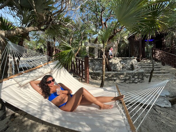 A hammock in a natural setting with stone steps and palm trees.