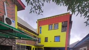 A multi-story building with a yellow and red facade, a covered outdoor area with a pool, and a brick exterior.
