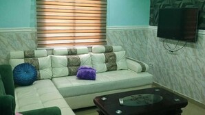 A living room with a sectional sofa, a coffee table, and a television mounted on the wall.