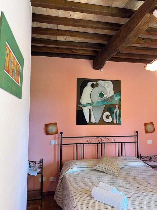A bedroom with a bed, a painting on the wall, and a wooden ceiling. - Agriturismo Melodie Toscane (Sorano)