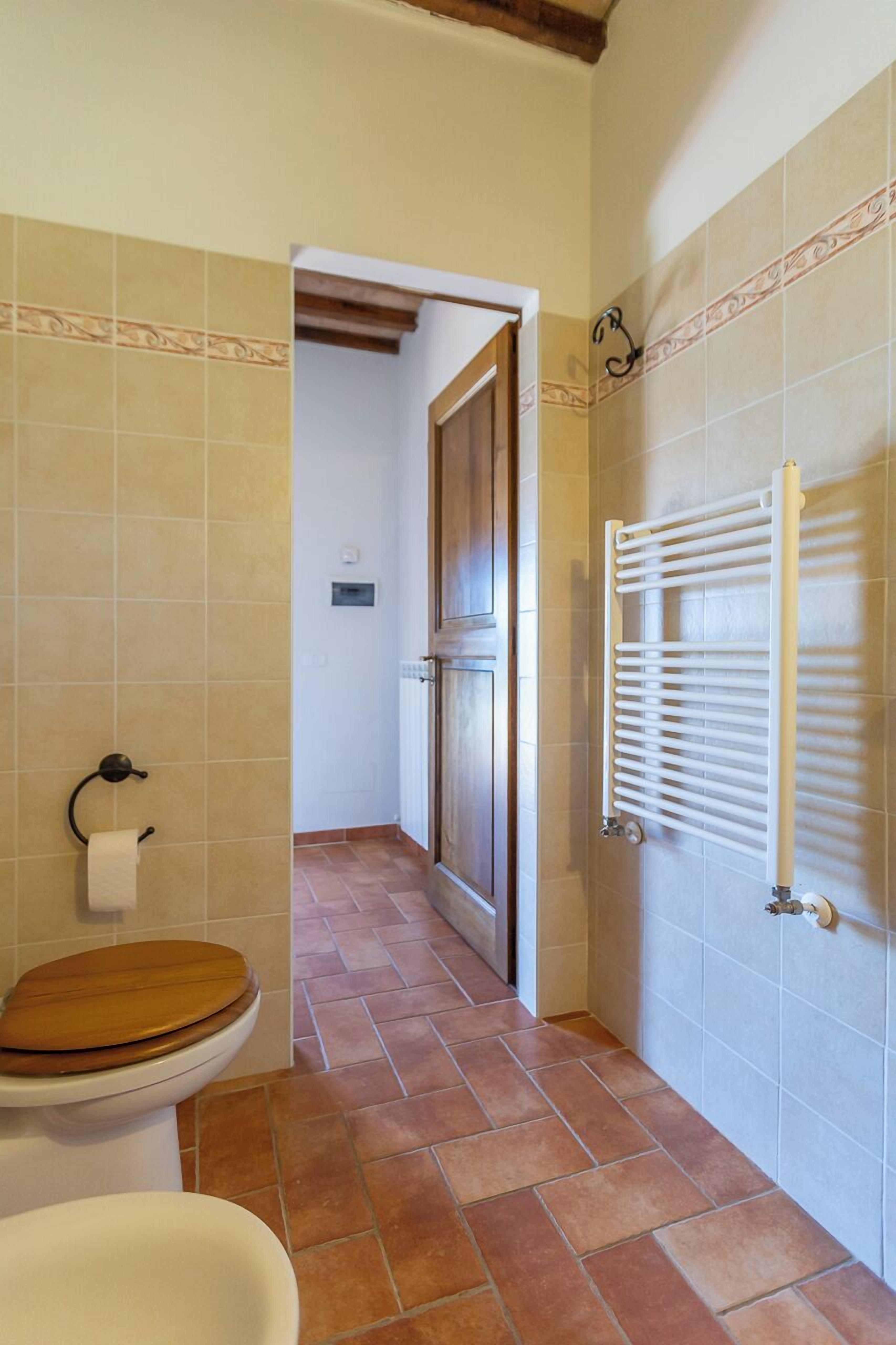 A bathroom with a wooden toilet, a white sink, and a towel rack.