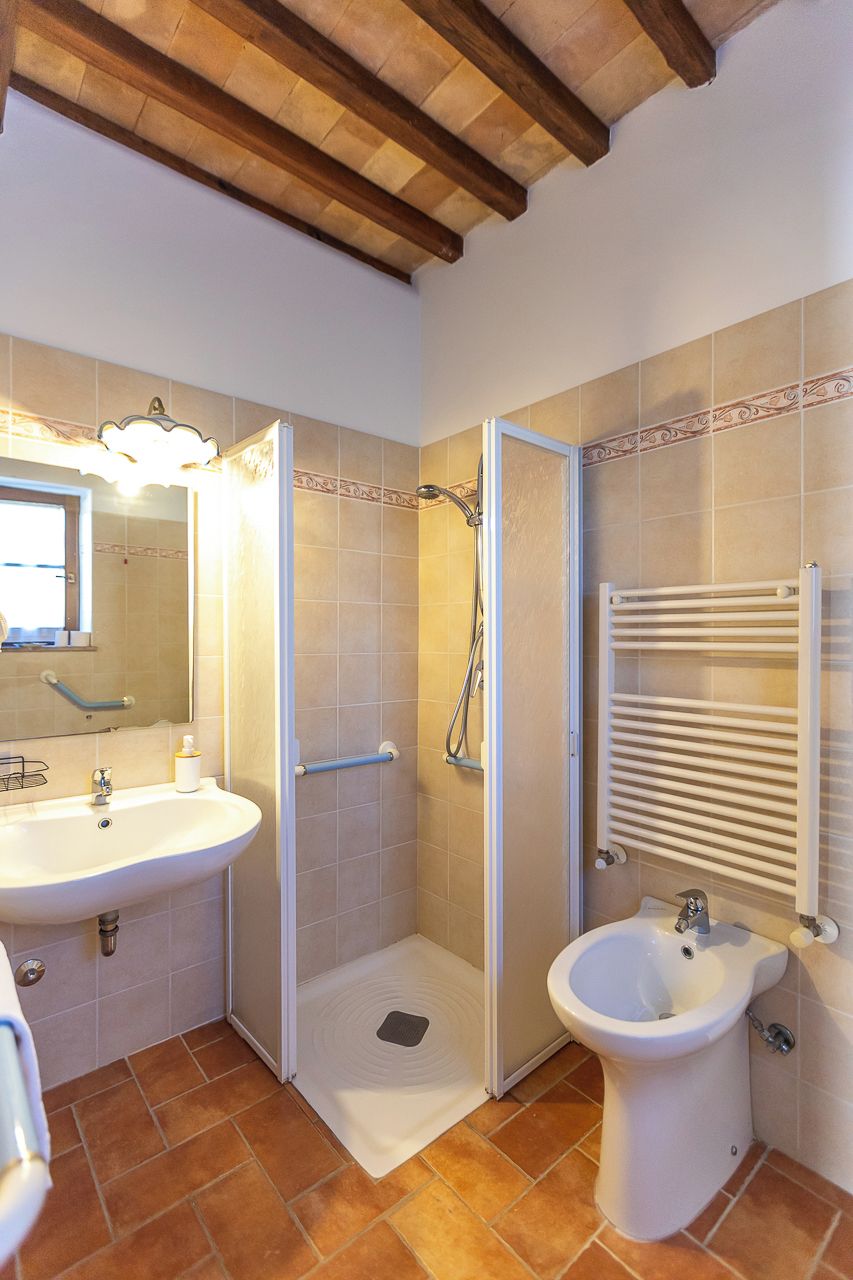 A bathroom with a sink, bidet, shower, and towel rack.