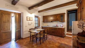 A kitchen with wooden cabinets, a dining table with chairs, a stove, and a refrigerator.