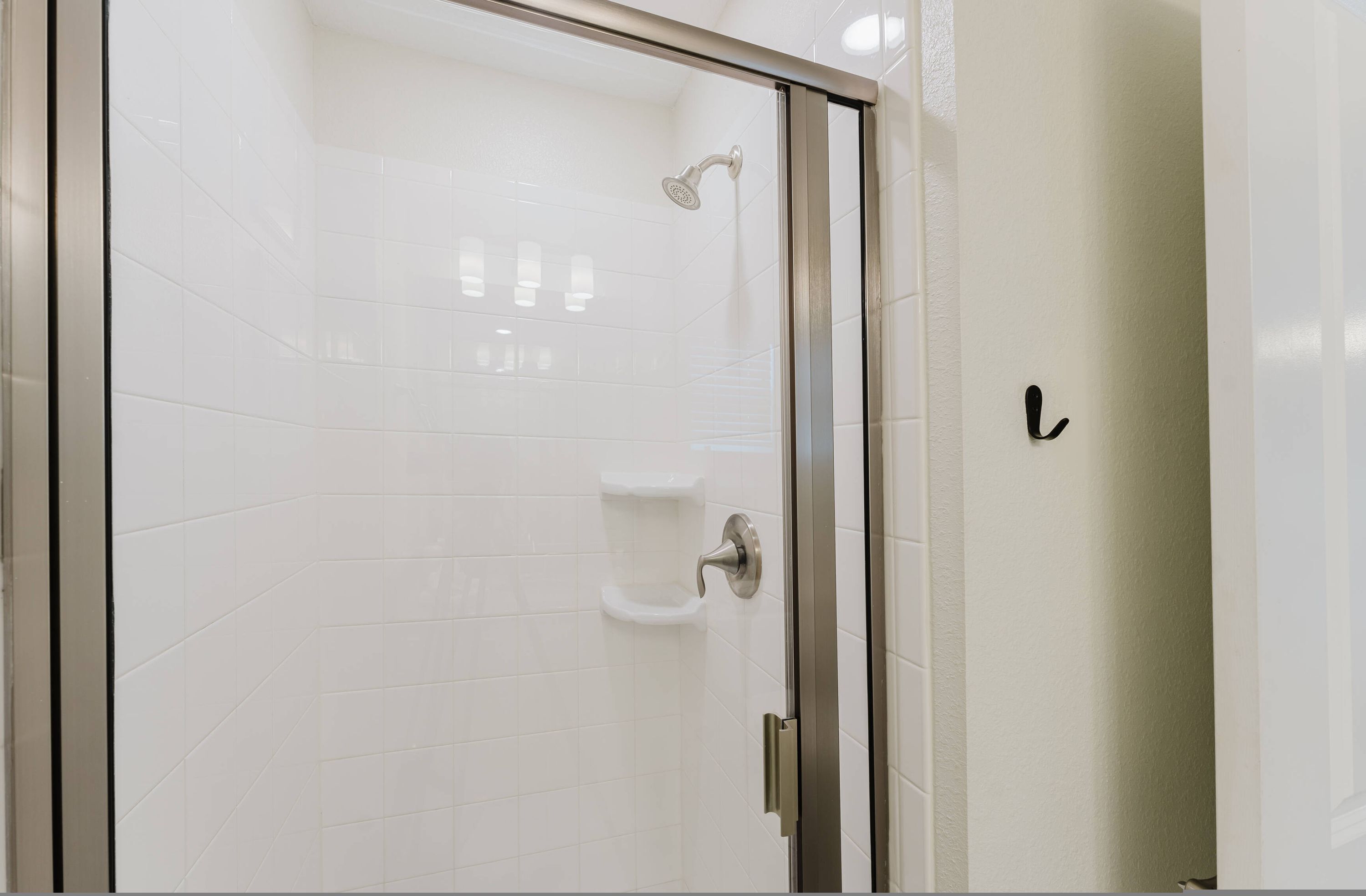 Una ducha con cerramiento de vidrio, cabezal de ducha manual y panel de control en la pared.