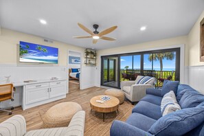 A modern living room with a large TV, comfortable seating, and a view of the outdoors.