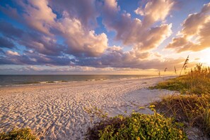 Ein Strand mit Sand, Wellen und einem bewölkten Himmel.