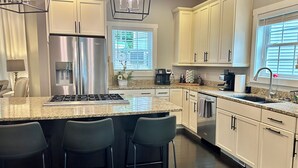Een moderne keuken met een centraal eiland, roestvrijstalen apparatuur en een groot raam voor veel daglicht.