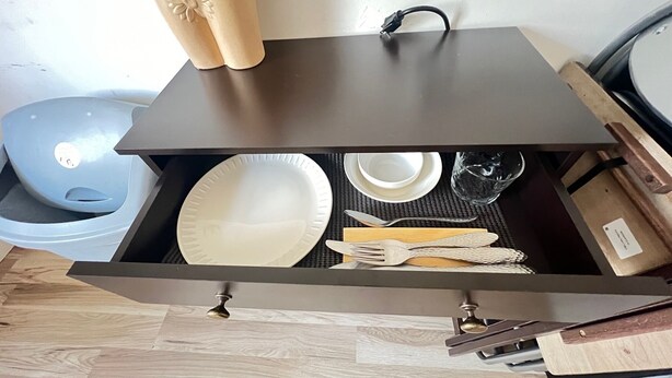 A kitchen drawer with a white plate, a white bowl, a spoon, and a knife.