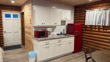 A compact kitchen with white cabinets, a red microwave, and a red refrigerator.