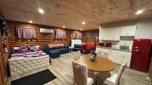 Et hyggeligt værelse i bjælkehytte-stil med seng, sofa og spisebord med stole.