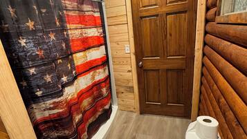 A bathroom with a wooden door, a shower curtain with a star pattern, and a toilet.