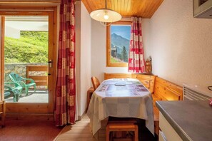 A cozy room with a wooden table, chairs, and a view of a mountain through a window. - Sherpa 11 on the snow front of Mottaret (Les Allues)