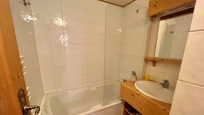 Een badkamer met een bad, een wastafel en een spiegel.