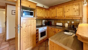 Een keuken met houten kastjes, een magnetron, een koffiezetapparaat en een broodrooster.