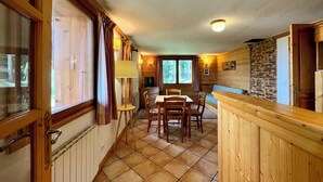 Een gezellig chaletinterieur met een eethoek, houten wanden en een accentmuur van steen.