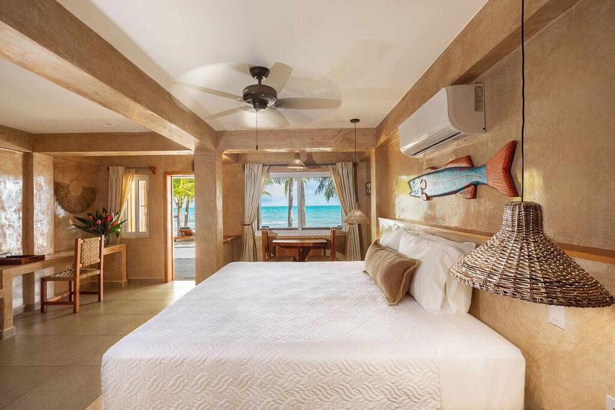 A spacious bedroom with a large bed, a ceiling fan, and a view of the ocean.