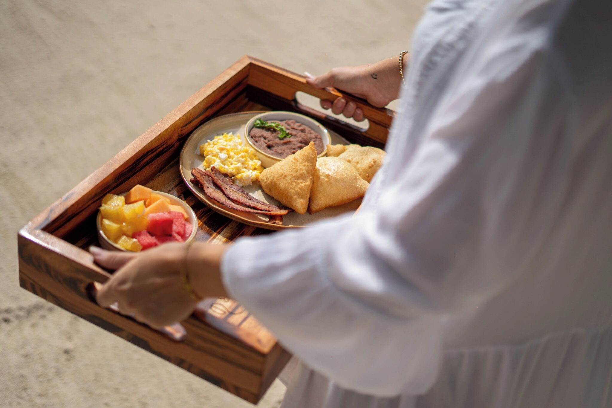 Una bandeja con diferentes alimentos, como huevos, frijoles y pan.