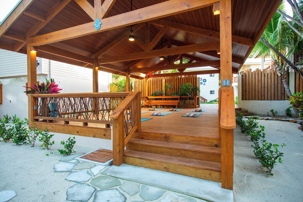 A wooden covered outdoor area with a wooden staircase leading to a deck with yoga mats.
