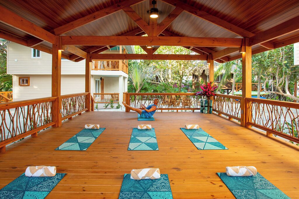 A wooden deck with yoga mats and a person doing a yoga pose.