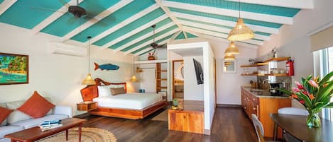A spacious room with a bed, a sofa, a dining table, and a kitchen area.