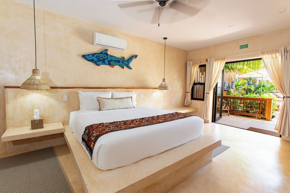 A spacious bedroom with a large bed, a ceiling fan, and a view of the outdoor area.