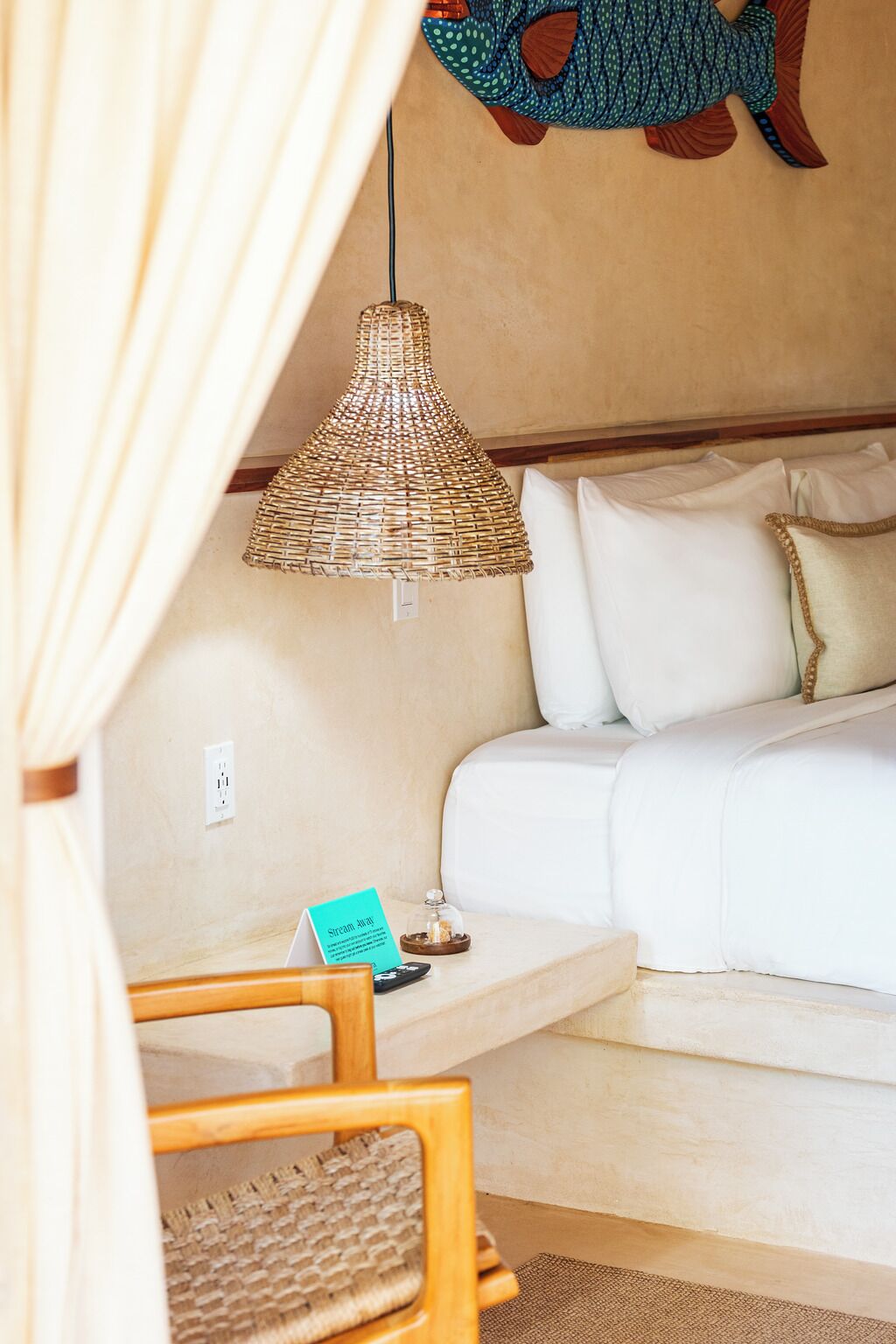 A cozy room with a white sofa, a wicker lamp, a small table with a card, and a wall decoration.