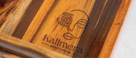 Ein hölzernes Tablett mit zwei Gläsern und einem Logo mit der Aufschrift 'Kalimera Beach Hotel'.
