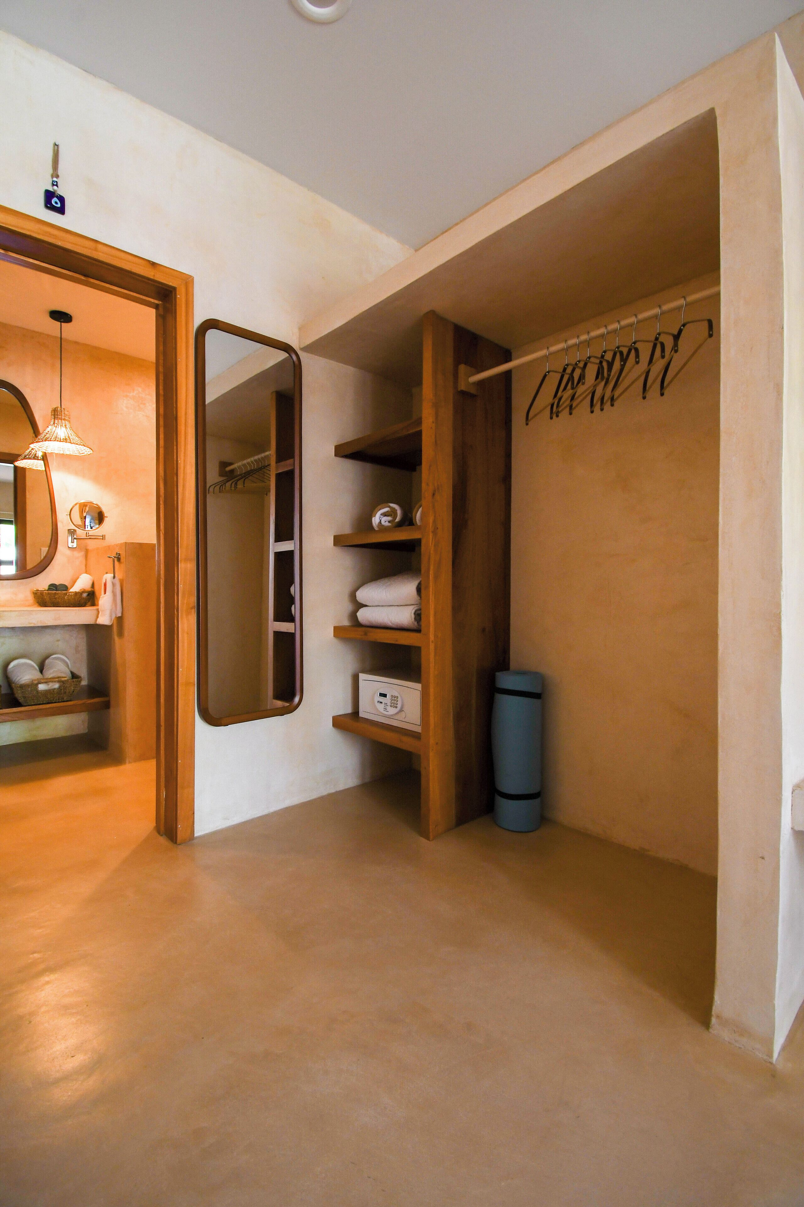 A compact bathroom with a wooden vanity, a mirror, a towel rack, and a small shelf with toiletries.