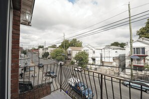 Une rue résidentielle bordée de maisons, avec des voitures et un ciel dégagé.
