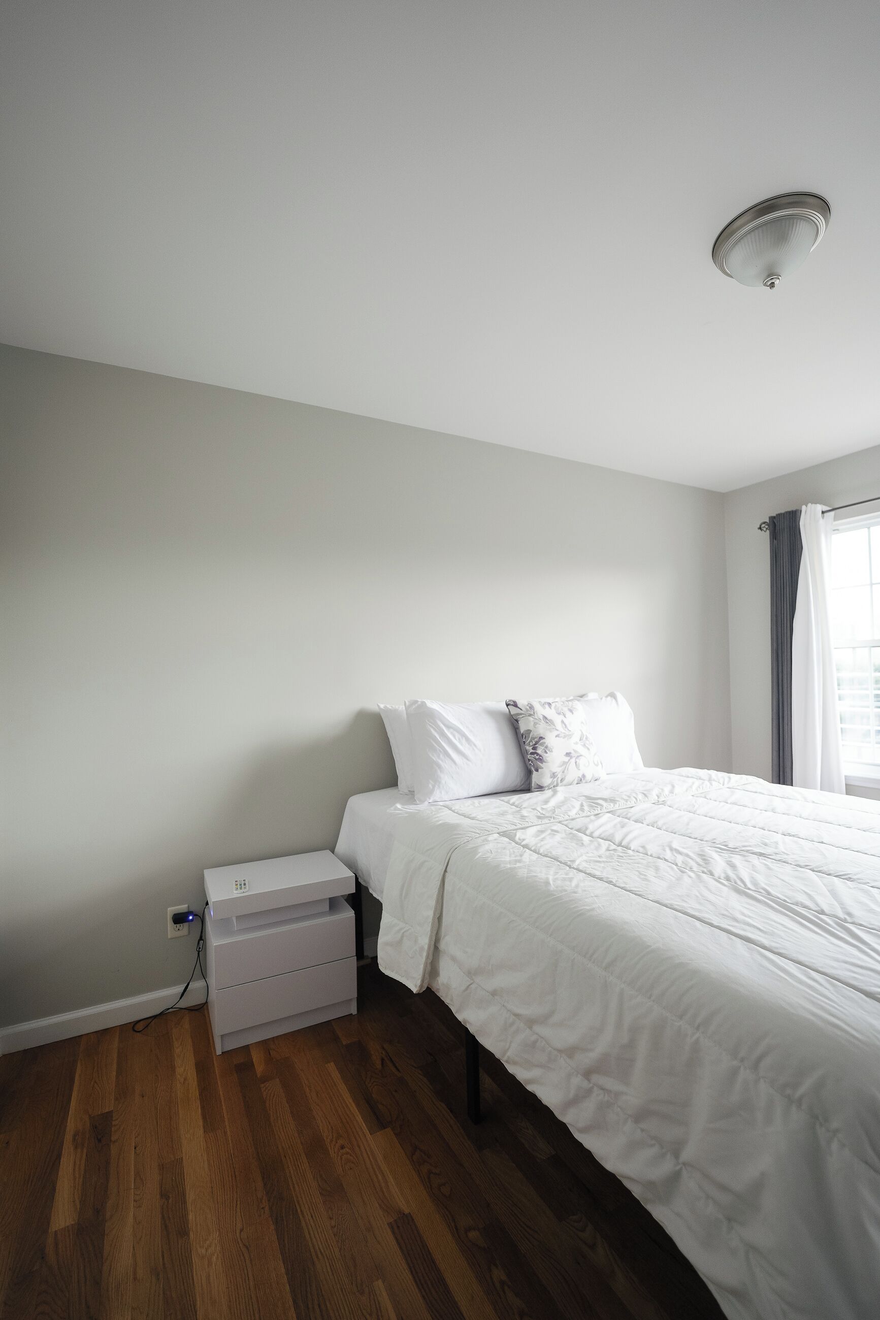 A bedroom with a bed, a nightstand, a dresser, and a ceiling light.