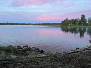 Un lago tranquillo con una riva boscosa e un cielo sereno.