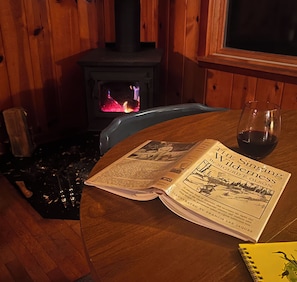 A book titled 'The Singing Wilderness' by Sigrid F. Olson on a table with a glass of red wine beside it.