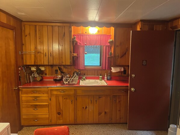 Una cucina compatta con mobili in legno, un piano di lavoro rosso e una finestra con vista.