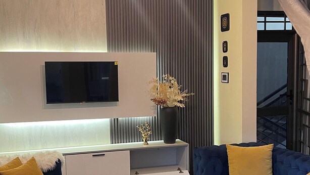 A modern living room with a sofa, a coffee table, and a TV mounted on the wall.