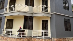 A multi-story residential building with balconies, a tiled ground floor, and a person standing on the lower level.