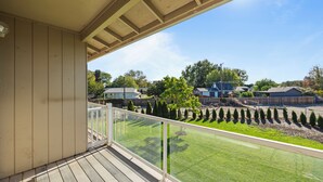 A balcony with a clear view of a well-maintained lawn and neighboring houses.