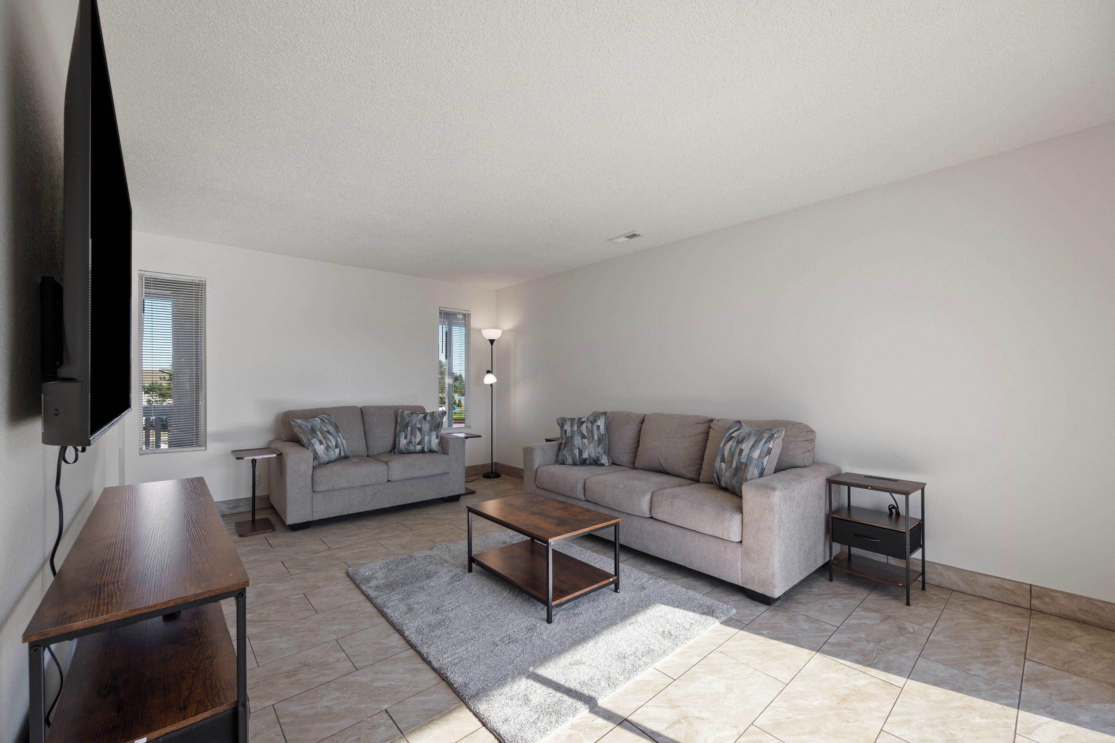 A living room with a sofa, a coffee table, a TV, and a lamp.