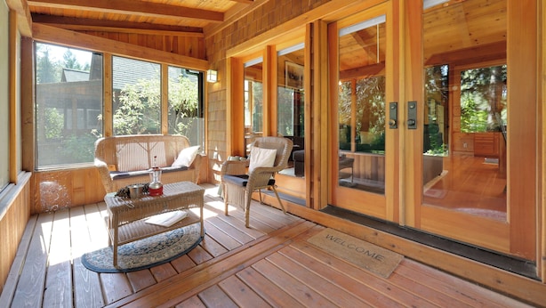 A wooden interior with a sofa, chairs, and a small table on a wooden deck.