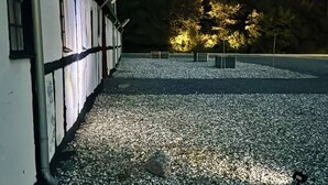 A gravel driveway leading to a building with a white facade and dark trim. - Svaleholm Gaard Roskilde -  Self check - in (Roskilde)