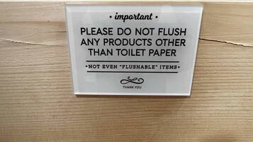 A sign on a wooden surface instructing not to flush any products other than toilet paper, even 'flushable' items.
