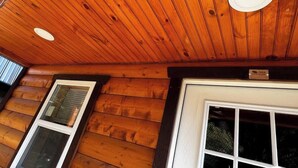 A wooden cabin interior with a sloped ceiling, a window, and a door. - Backwoods Bungalow (Pikeville)