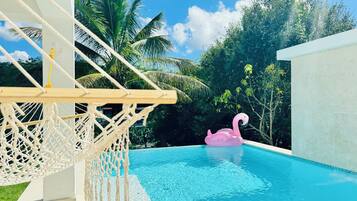 Une piscine avec un hamac en macramé et un flotteur en forme de flamant rose.