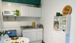A modern kitchen with white cabinetry, a microwave, a sink, and a dining area with a white table set for four. - Romantica Casa de Campo con Piscina Privada (fanduca cidra)
