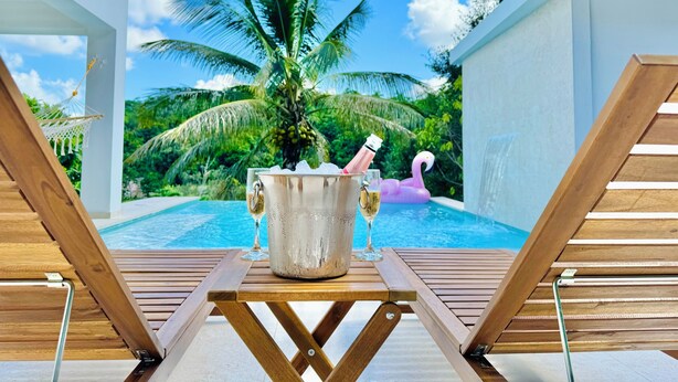 A poolside area with a wooden table, lounge chairs, a champagne bucket, and a flamingo float. - Romantica Casa de Campo con Piscina Privada (fanduca cidra)