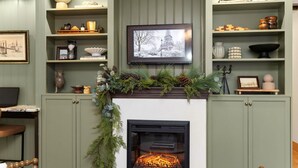 A cozy living room with a fireplace, shelves with decorative items, and a framed picture of the Eiffel Tower. - 4Bdrm Muskoka Retreat Fire Table, Games, Netflix (Port Carling)
