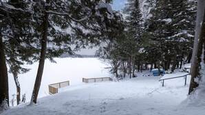 A snowy landscape with a wooden deck and a blue vehicle in the background. - 4Bdrm Muskoka Retreat Fire Table, Games, Netflix (Port Carling)