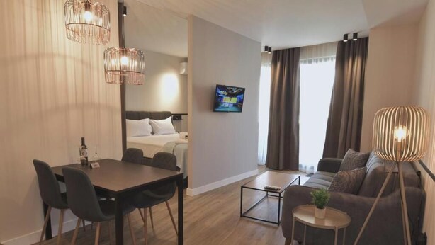 Ein modernes Hotelzimmer mit Essbereich, einer Couch, einem Fernseher und einer Lampe.