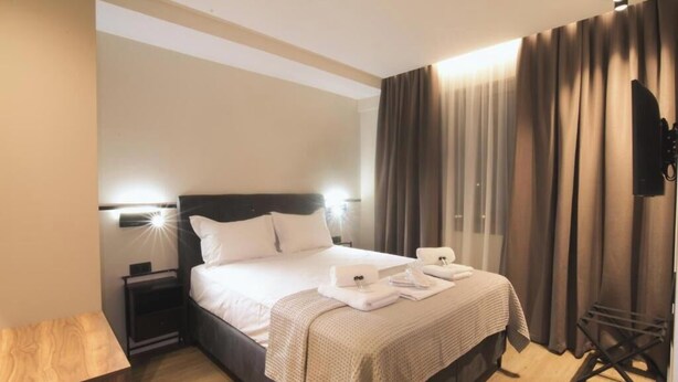 A hotel room with a bed, bedside tables, a TV, and curtains. - Superior Apartment with City View (Athens)