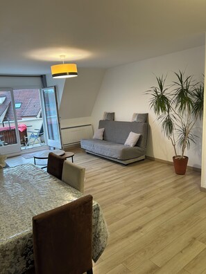 En moderne stue med en sofa, et spisebord og en potteplante.